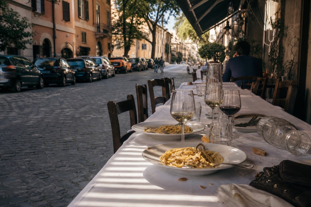 A table set with Roman pasta dishes and wine glasses for a group