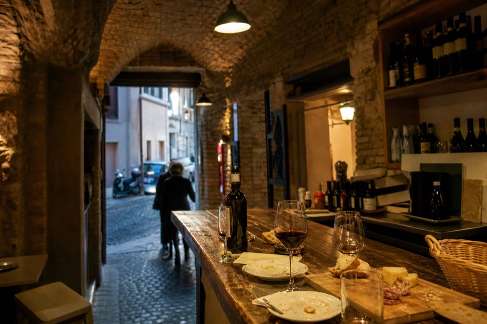 Wine glasses and small plates on the wooden counter of a small Roman enoteca in the evening