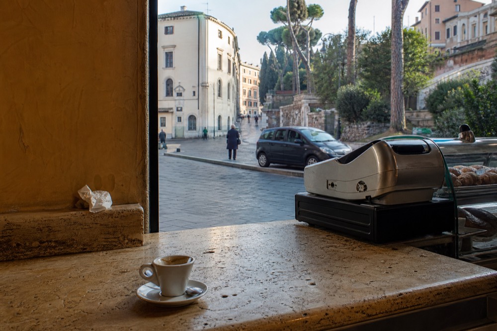 A Roman bar counter with a till and pastries under glass
