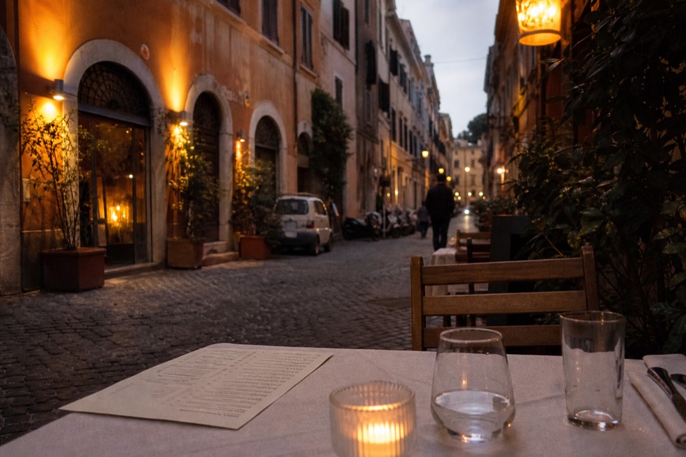 A set trattoria table in Rome with a printed menu beside it