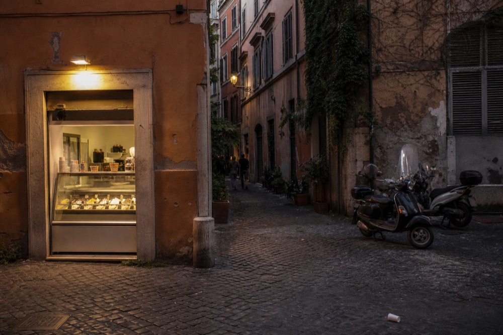 A gelateria storefront on a quiet Roman street in the evening