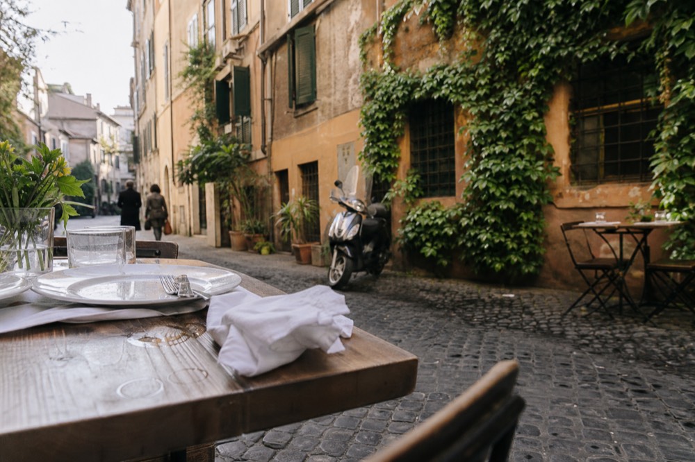 A close view of restaurant tables set for dinner on a cobbled street in Trastevere