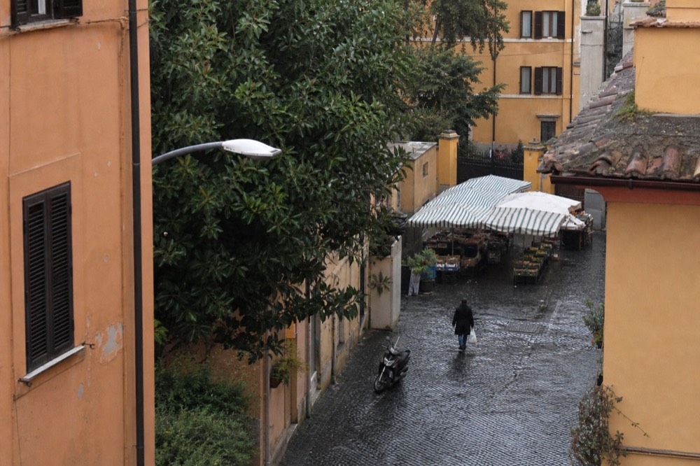 A Testaccio side street with a market entrance and awnings in the distance