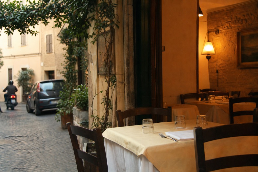 A traditional Rome trattoria dining room set for dinner with empty tables and folded napkins