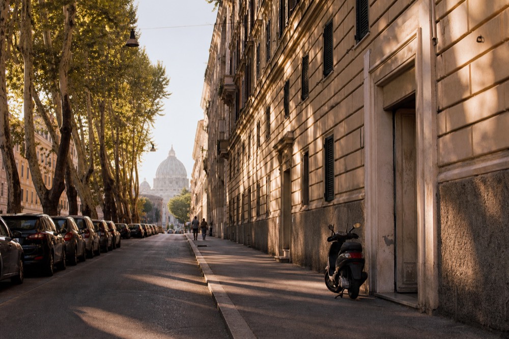 A residential Prati street with the Vatican dome visible in the distance