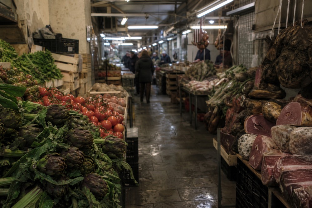 A covered market aisle with produce and food stalls in Prati