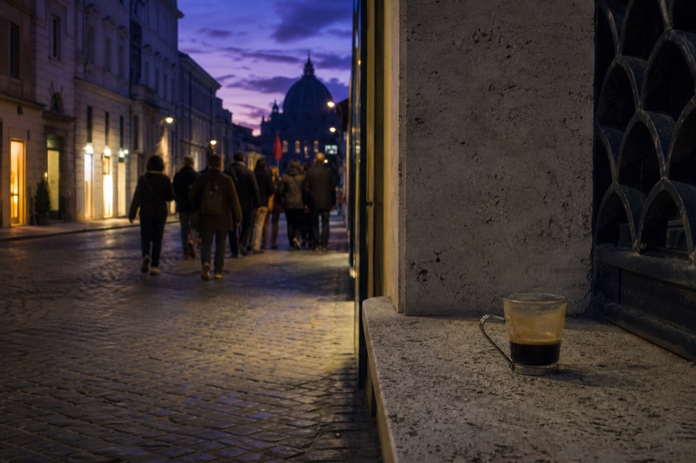 A small group walking through an evening street near the Vatican with a guide