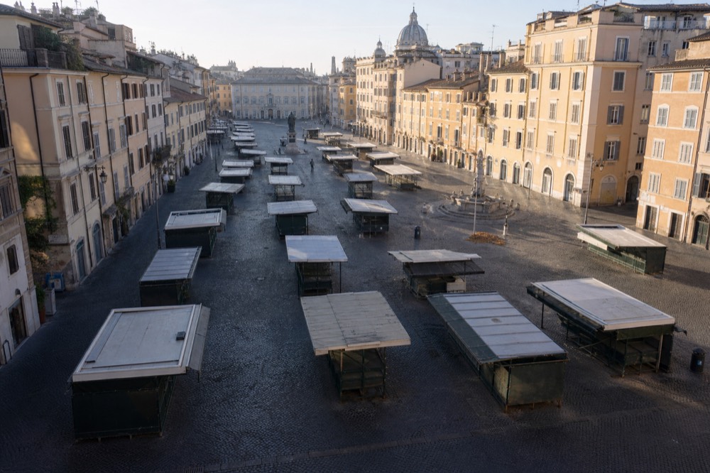 A quiet Roman piazza in early morning light with shuttered market stalls