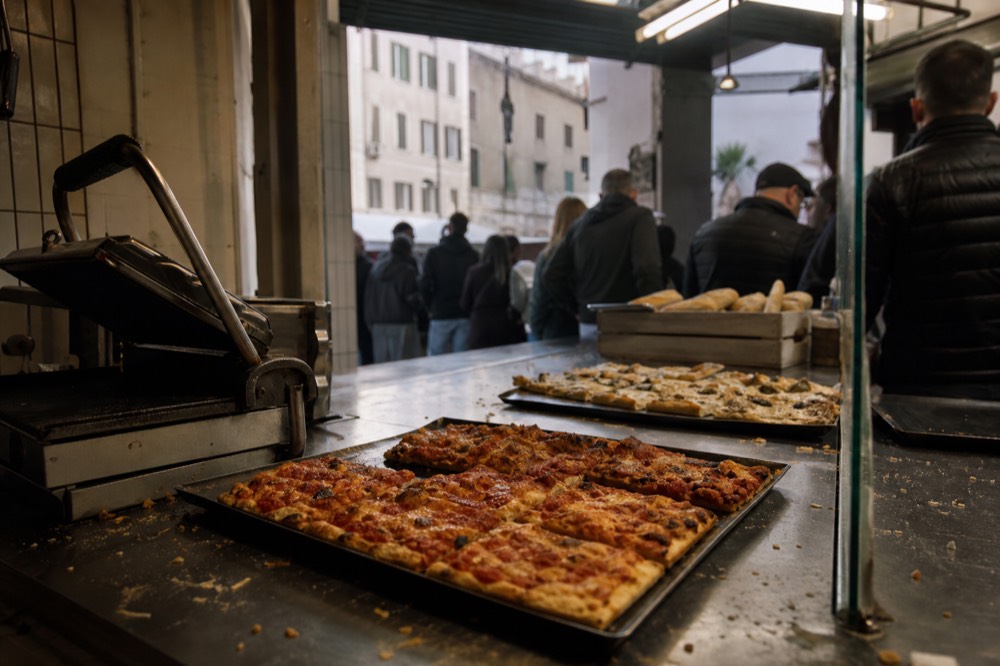 A market stall counter with trays of baked flatbread pizza