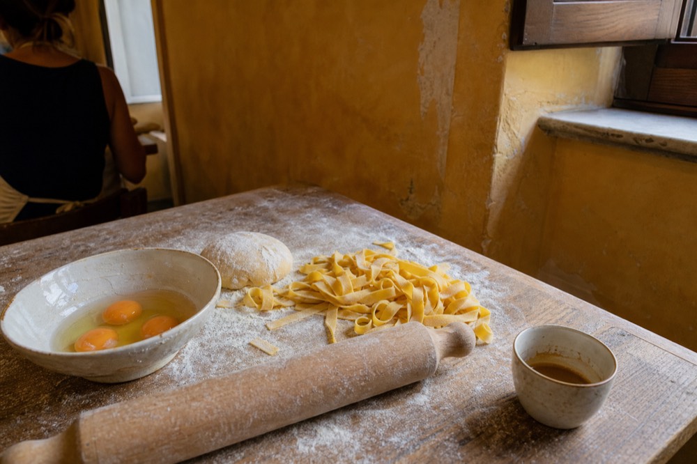 A cooking class table with flour, eggs and fresh pasta dough ready to roll