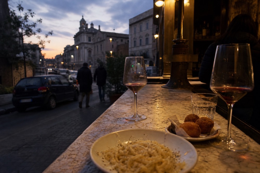 Glasses of Italian red wine and small plates of Roman food arranged on a bar counter