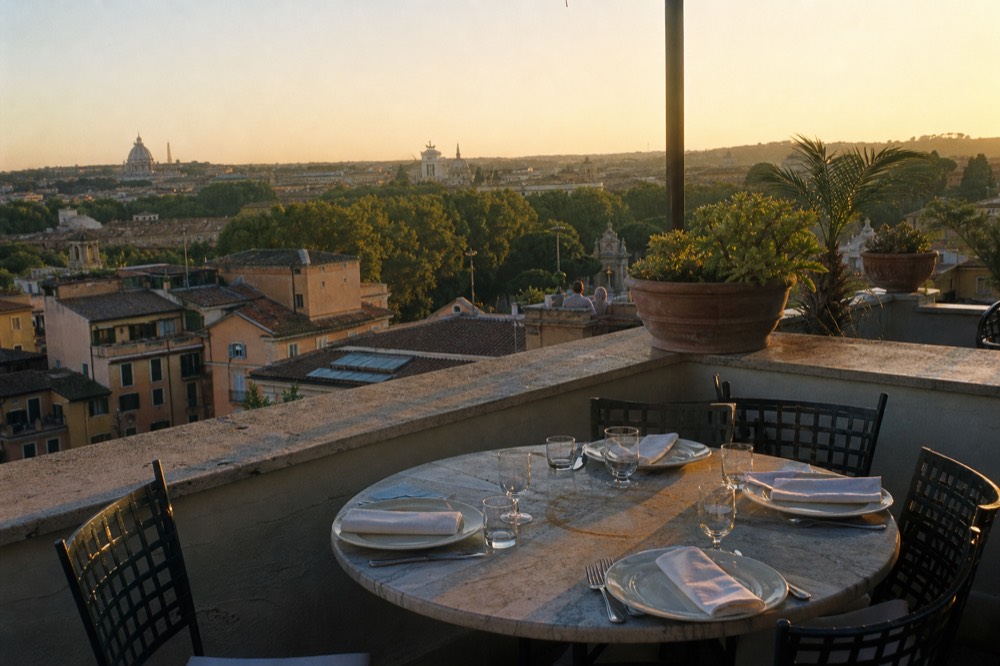 Rooftop terrace table set for dinner above Rome at golden hour