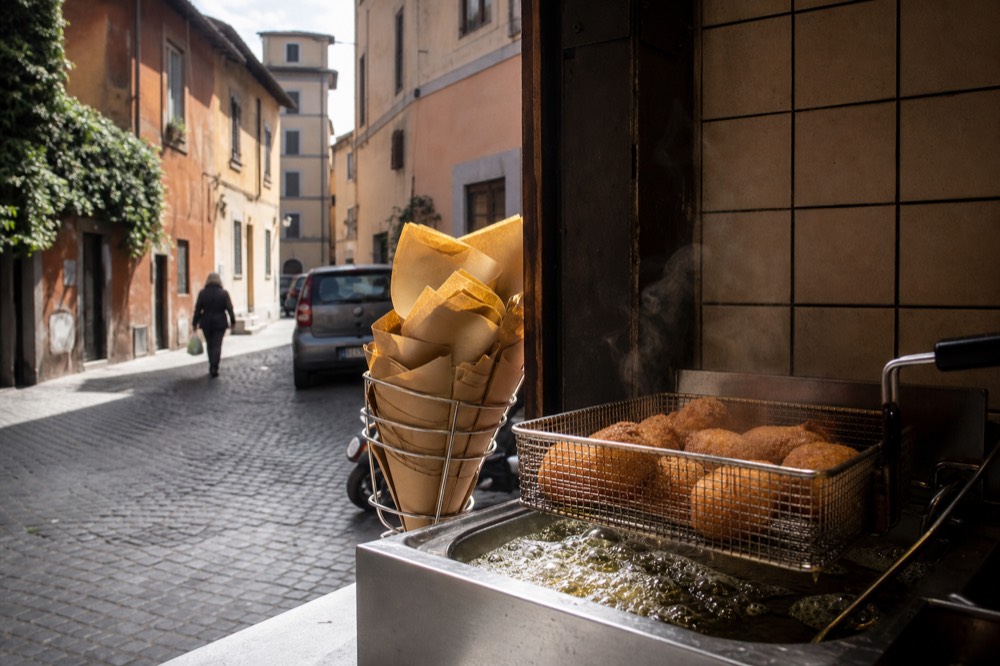 Supplì rice croquettes in a fryer basket at a Roman takeaway counter