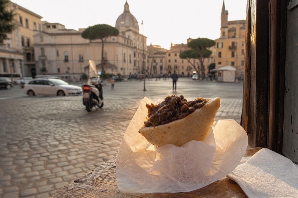 A triangular pocket of bread filled with a dark meat stew held in two hands