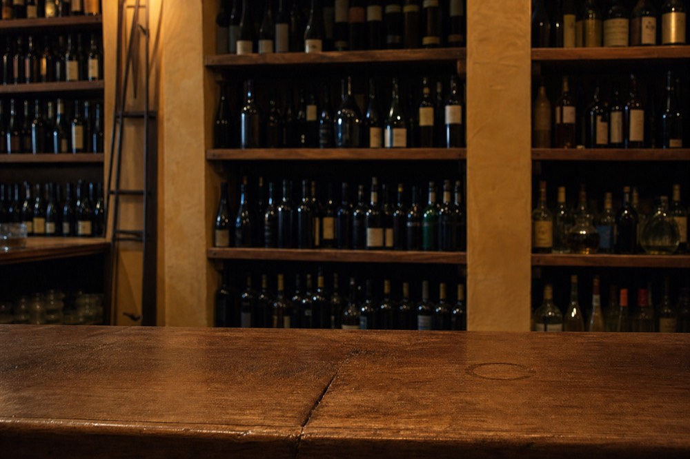 Wine bottles racked behind a wooden enoteca counter in Rome