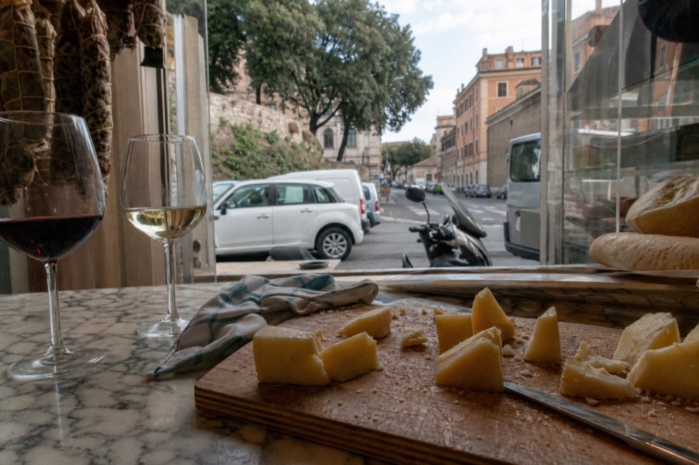 A marble enoteca counter set with wine glasses and a cheese board in Rome