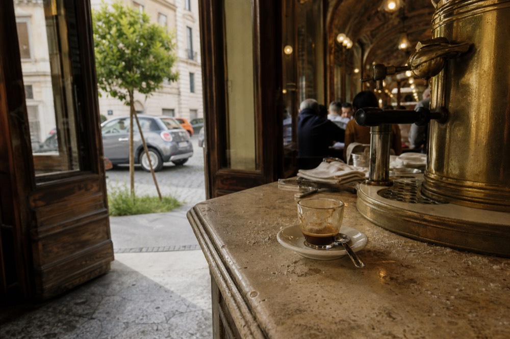 The interior of a historic Roman café with a marble counter and coffee machines