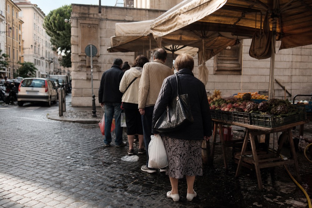 A market stall with fresh produce and a queue of people
